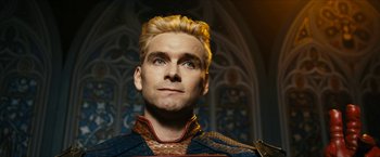 Movie still from “The Boys” (2019), created by Eric Kripke – A person with blond hair wearing a suit; Close Up shot, Low angle