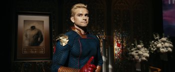 Movie still from “The Boys” (2019), created by Eric Kripke – A man with blonde hair wearing a blue and red outfit; Medium shot, Low angle