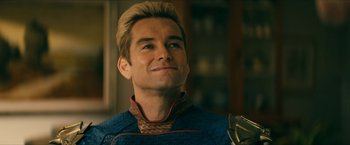 Movie still from “The Boys” (2019), created by Eric Kripke – A man with blonde hair and a blue shirt is smiling; Close Up shot, Over the shoulder angle