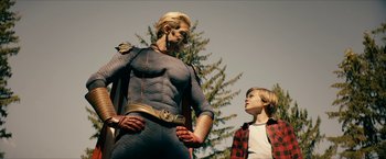 Movie still from “The Boys” (2019), created by Eric Kripke – A man and a boy standing next to each other in front of a tree; Medium shot, Over the shoulder angle