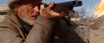 Movie still from “3:10 to Yuma” (2007), directed by James Mangold – An old man holding a gun while wearing a hat; Close Up shot, Low angle