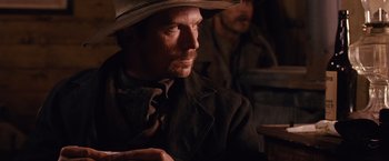 Movie still from “3:10 to Yuma” (2007), directed by James Mangold – A man with a cowboy hat on sitting in a room; Close Up shot, Over the shoulder angle