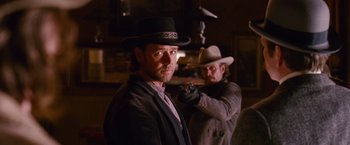 Movie still from “3:10 to Yuma” (2007), directed by James Mangold – A man in a cowboy hat is holding a gun; Medium shot, Over the shoulder angle