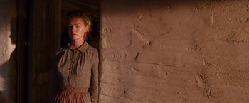 Movie still from “3:10 to Yuma” (2007), directed by James Mangold – A woman standing in front of a brick wall; Medium shot, Over the shoulder angle