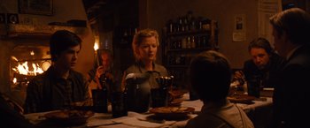 Movie still from “3:10 to Yuma” (2007), directed by James Mangold – A woman sitting at a dinner table in front of two other people; Medium shot, Over the shoulder angle
