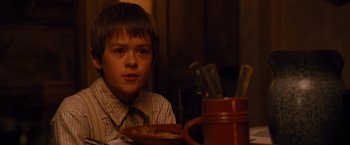 Movie still from “3:10 to Yuma” (2007), directed by James Mangold – A boy sitting at a table with a plate of food in front of him; Close Up shot, High angle