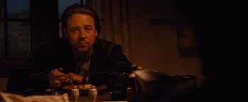 Movie still from “3:10 to Yuma” (2007), directed by James Mangold – A man sitting at a table with a drink in front of him; Medium shot, Over the shoulder angle