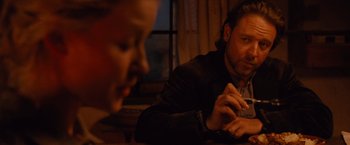 Movie still from “3:10 to Yuma” (2007), directed by James Mangold – A man sitting at a table with another man in the background; Medium shot, Over the shoulder angle