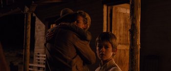 Movie still from “3:10 to Yuma” (2007), directed by James Mangold – A man hugging another man while a boy looks on; Medium shot, Over the shoulder angle