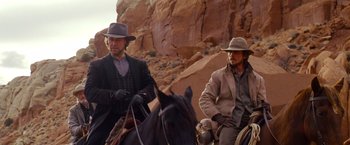 Movie still from “3:10 to Yuma” (2007), directed by James Mangold – A couple of men riding horses down a dirt road; Medium shot, Low angle