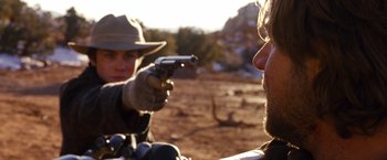 Movie still from “3:10 to Yuma” (2007), directed by James Mangold – A man and a woman holding a gun in a field; Close Up shot, Over the shoulder angle