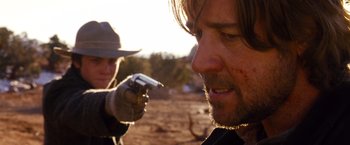 Movie still from “3:10 to Yuma” (2007), directed by James Mangold – A man holding a gun in front of another man in a hat; Close Up shot, Over the shoulder angle