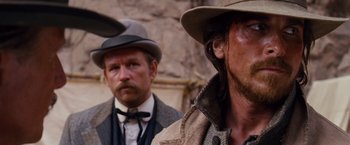 Movie still from “3:10 to Yuma” (2007), directed by James Mangold – Two men in hats and suits standing next to each other; Close Up shot, Over the shoulder angle