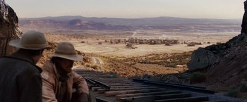 Movie still from “3:10 to Yuma” (2007), directed by James Mangold – A man standing on top of train tracks near a field; Wide shot, High angle
