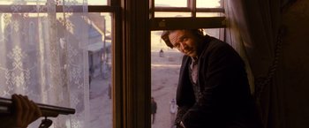 Movie still from “3:10 to Yuma” (2007), directed by James Mangold – A man standing in front of a window; Medium shot, Over the shoulder angle