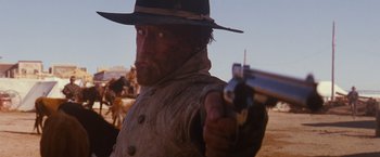 Movie still from “3:10 to Yuma” (2007), directed by James Mangold – A man holding a gun while standing in a field; Close Up shot, Low angle