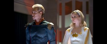 Movie still from “The Boys” (2019), created by Eric Kripke – A man and a woman dressed in costumes standing next to each other; Medium shot, Over the shoulder angle