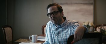 Movie still from “The Boys” (2019), created by Eric Kripke – A man sitting at a table with a cup of coffee in front of him; Close Up shot, Over the shoulder angle