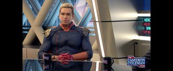 Movie still from “The Boys” (2019), created by Eric Kripke – A man sitting at a table with a cup of coffee; Medium shot, Over the shoulder angle