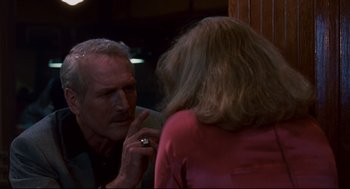 Movie still from “The Color of Money” (1986), directed by Martin Scorsese – An older man looking in the mirror while talking to a younger woman; Close Up shot, Over the shoulder angle