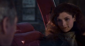 Movie still from “The Color of Money” (1986), directed by Martin Scorsese – A woman with long red curly hair holding onto a red umbrella; Close Up shot, Over the shoulder angle