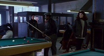 Movie still from “The Color of Money” (1986), directed by Martin Scorsese – A group of people standing around a pool table; Wide shot, Over the shoulder angle