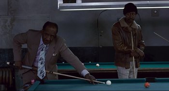 Movie still from “The Color of Money” (1986), directed by Martin Scorsese – A man in a suit and tie playing a game of billiards; Medium shot, High angle