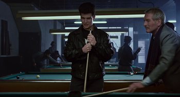 Movie still from “The Color of Money” (1986), directed by Martin Scorsese – A man holding a pool stick while standing in front of a pool table; Medium shot, Over the shoulder angle