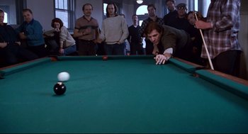 Movie still from “The Color of Money” (1986), directed by Martin Scorsese – A group of people watching a man play a game of billiards; Medium shot, High angle