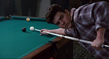 Movie still from “The Color of Money” (1986), directed by Martin Scorsese – A young man playing a game of billiards; Medium shot, Over the shoulder angle