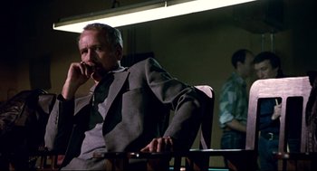 Movie still from “The Color of Money” (1986), directed by Martin Scorsese – An older man sitting in a chair talking on a phone; Medium shot, Over the shoulder angle