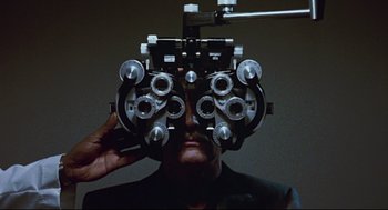 Movie still from “The Color of Money” (1986), directed by Martin Scorsese – A man is looking through the lens of an ophthalmoscope; Extreme Close Up shot, Overhead angle