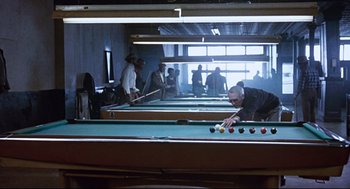Movie still from “The Color of Money” (1986), directed by Martin Scorsese – A group of people playing a game of billiards; Wide shot, Over the shoulder angle