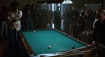 Movie still from “The Color of Money” (1986), directed by Martin Scorsese – A group of people standing around a billiards table; Wide shot, High angle