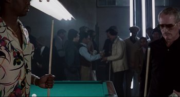 Movie still from “The Color of Money” (1986), directed by Martin Scorsese – A group of men standing around a pool table; Medium shot, Over the shoulder angle