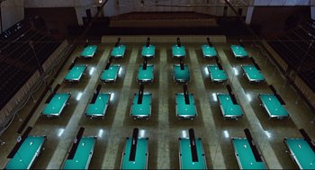 Movie still from “The Color of Money” (1986), directed by Martin Scorsese – Rows of pool tables are lined up in an empty pool hall; Extreme Wide shot, High angle