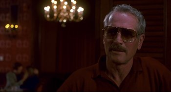 Movie still from “The Color of Money” (1986), directed by Martin Scorsese – An older man wearing glasses in front of a chandelier; Close Up shot, Low angle