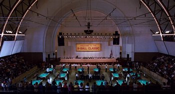 Movie still from “The Color of Money” (1986), directed by Martin Scorsese – A group of people sitting at tables in front of an audience; Extreme Wide shot, High angle