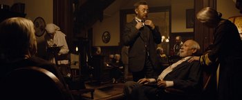 Movie still from “The Curious Case of Benjamin Button” (2008), directed by David Fincher – A man in a suit and tie standing in front of a mirror; Medium shot, Over the shoulder angle