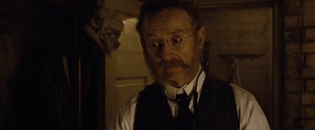Movie still from “The Curious Case of Benjamin Button” (2008), directed by David Fincher – An old man with a beard wearing glasses and a vest; Close Up shot, Over the shoulder angle