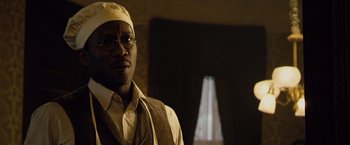 Movie still from “The Curious Case of Benjamin Button” (2008), directed by David Fincher – A man wearing a hat and glasses in front of a window; Close Up shot, Low angle