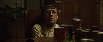 Movie still from “The Curious Case of Benjamin Button” (2008), directed by David Fincher – An older man sitting at a table in front of cans of food; Close Up shot, Low angle