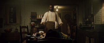 Movie still from “The Curious Case of Benjamin Button” (2008), directed by David Fincher – A man standing in front of a table in a kitchen; Medium shot, Over the shoulder angle
