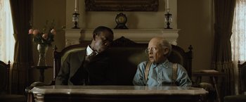 Movie still from “The Curious Case of Benjamin Button” (2008), directed by David Fincher – Two men sitting on a couch in front of a fireplace; Medium shot, Over the shoulder angle