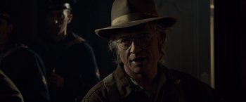 Movie still from “The Curious Case of Benjamin Button” (2008), directed by David Fincher – A man wearing a hat and glasses in the dark; Close Up shot, Over the shoulder angle