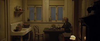 Movie still from “The Curious Case of Benjamin Button” (2008), directed by David Fincher – An older man sitting at a table in front of a window; Wide shot, Over the shoulder angle