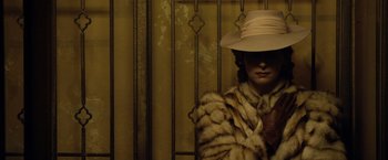 A woman wearing a fur coat and a hat in front of a wall
