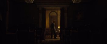 Movie still from “The Curious Case of Benjamin Button” (2008), directed by David Fincher – A man standing in the dark in front of an open doorway; Wide shot, Low angle