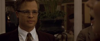 Movie still from “The Curious Case of Benjamin Button” (2008), directed by David Fincher – A person wearing glasses and a suit; Close Up shot, Over the shoulder angle