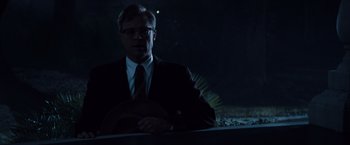 Movie still from “The Curious Case of Benjamin Button” (2008), directed by David Fincher – A man in a suit and tie standing in the dark; Medium shot, Low angle